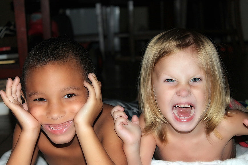 Two children making funny faces and expressions indoors