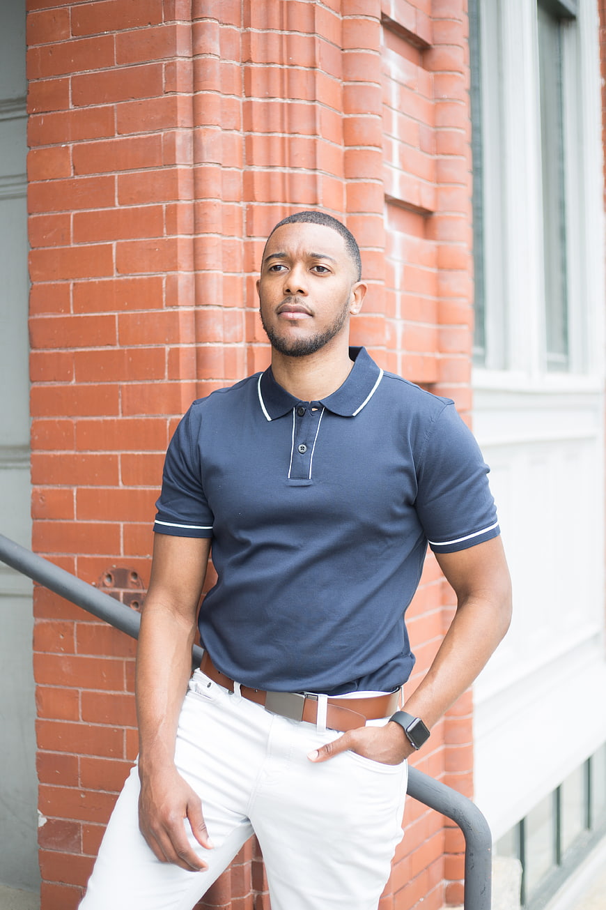 Confident young black man in navy polo and white pants