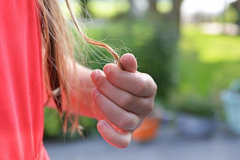 Child's hand holding hair strand in garden
