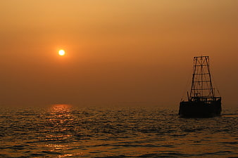 Silhouette of fishing boat on calm sea at golden sunset