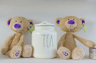Two teddy bears flanking a white ceramic tea jar