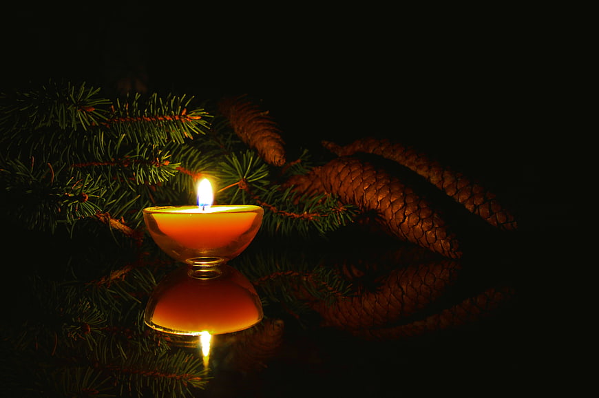 Lit Advent Candle with Pine Branches and Cones