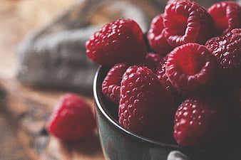 Close-up of fresh red raspberries in a rustic ceramic bowl