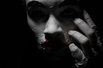 Close-up portrait of a creepy clown with cracked white face paint