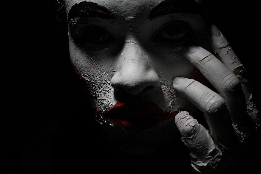 Close-up portrait of a creepy clown with cracked white face paint