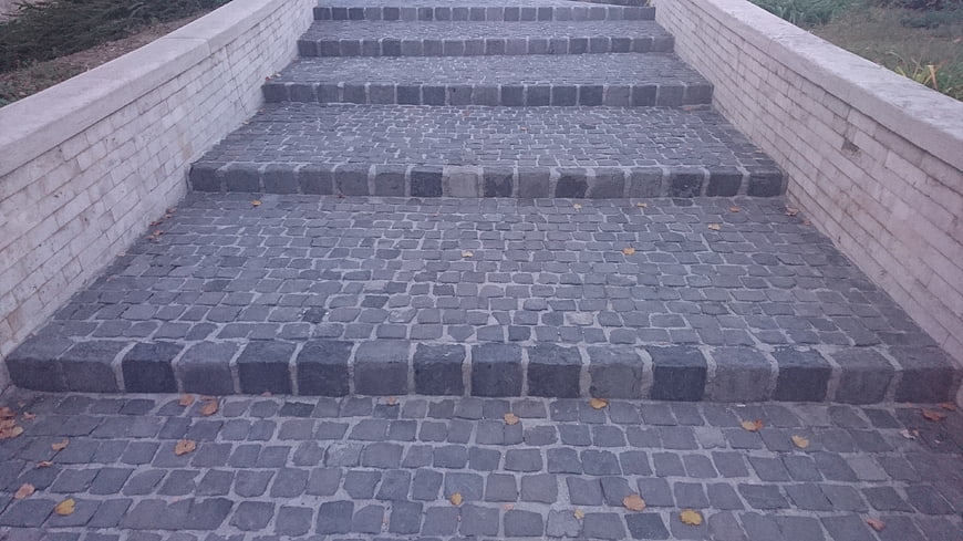Gray cobblestone stairs with brick walls and fallen leaves