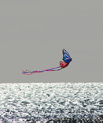 Colorful butterfly kite flying over sparkling ocean waves