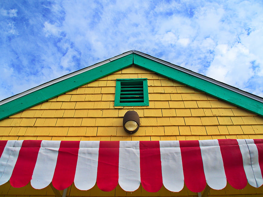 Colorful yellow building facade with red and white striped awning