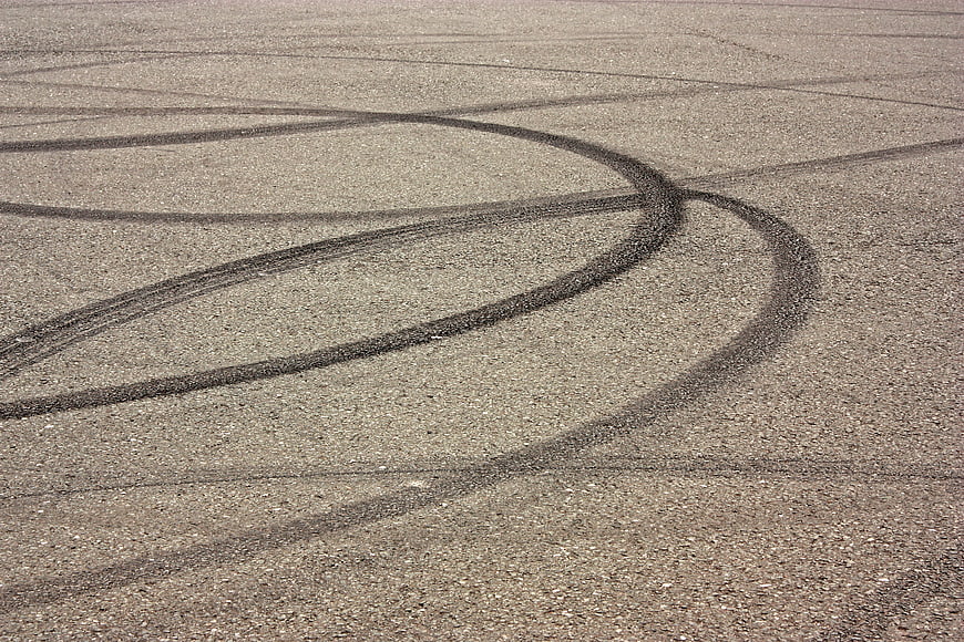 Curved black tire skid marks on gray asphalt road surface