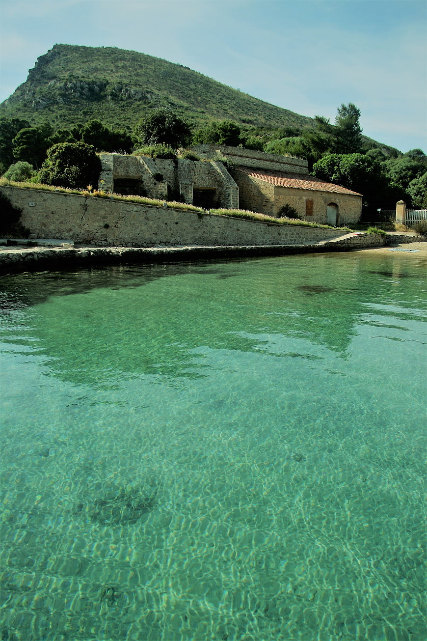 Crystal clear turquoise water with stone buildings and green hill