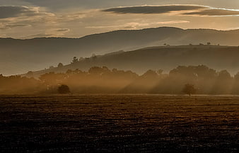 Golden Sunbeams Through Misty Hills at Sunrise