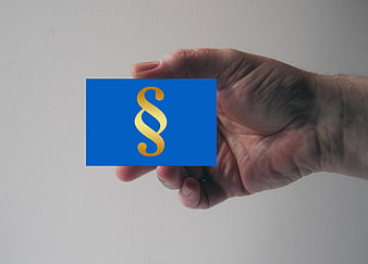 Hand holding blue card with gold paragraph symbol
