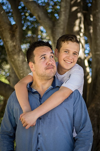 Father Carrying Smiling Son On Shoulders In Park