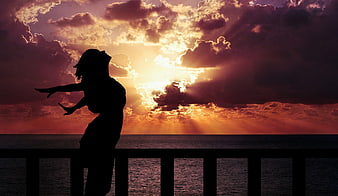Silhouette of Woman Enjoying Sunset by the Ocean