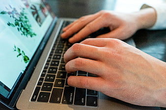 Close-up of hands typing on laptop keyboard
