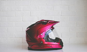 Red motocross helmet on white brick wall background