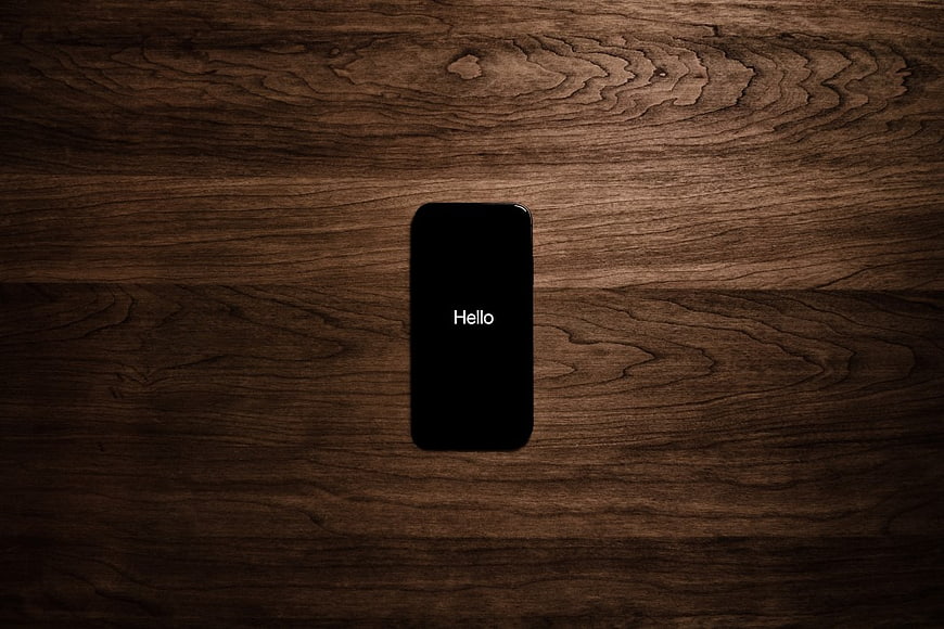 Smartphone with Hello Text on Dark Wood Background
