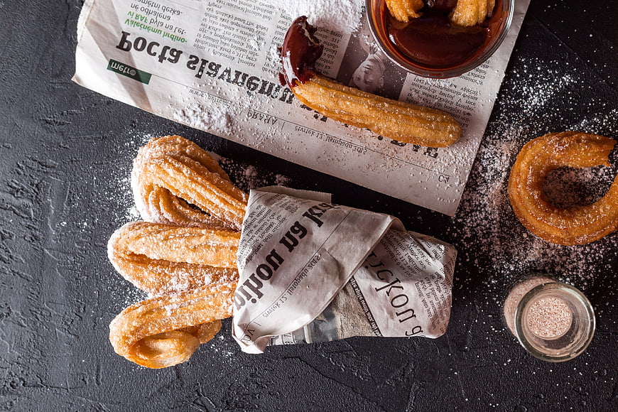 Overhead view of churros with chocolate sauce and cinnamon sugar