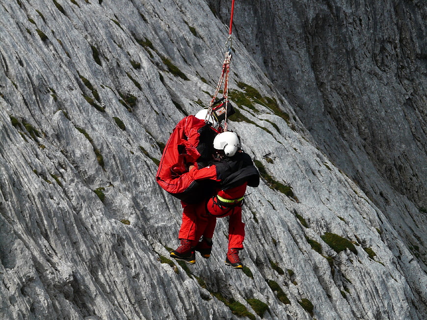 Mountain rescue team abseiling down steep rocky cliff face