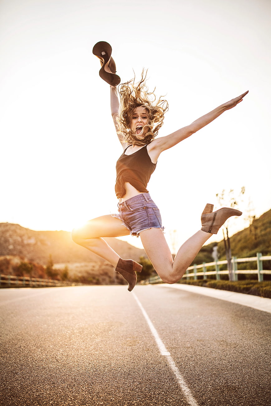 Happy Woman Jumping on Road at Sunset