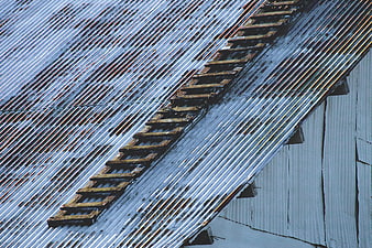 Weathered wooden ladder on corrugated metal roof