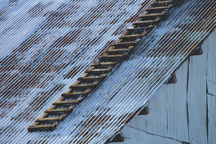 Weathered wooden ladder on corrugated metal roof