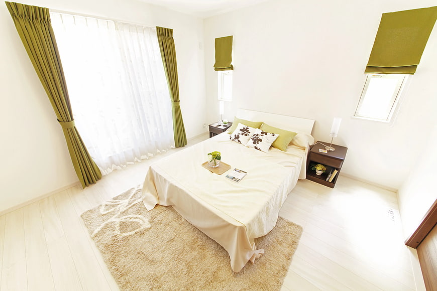 Bright Bedroom Interior with Beige Bedding and Green Curtains