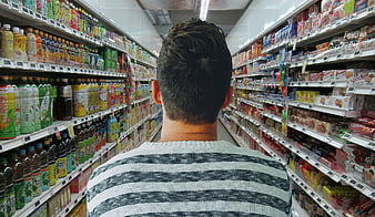 Man shopping in supermarket aisle with colorful products