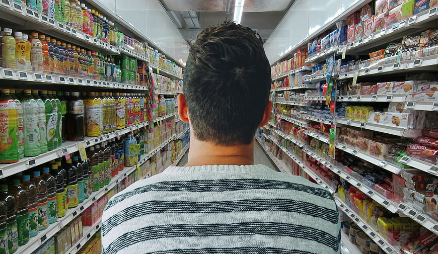 Man shopping in supermarket aisle with colorful products