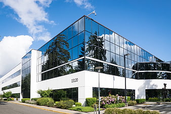 Modern white office building with glass facade and blue sky