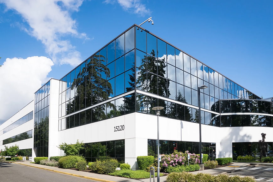 Modern white office building with glass facade and blue sky