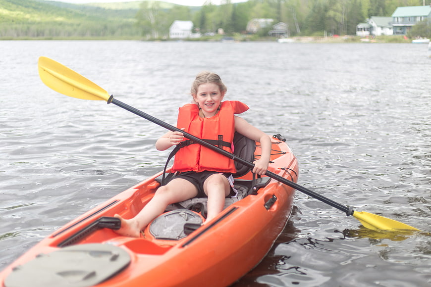 Young Girl Kayaking on Lake with Orange Life Jacket
