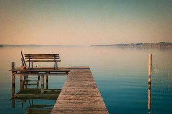 Serene Wooden Dock with Bench on Calm Lake at Sunset