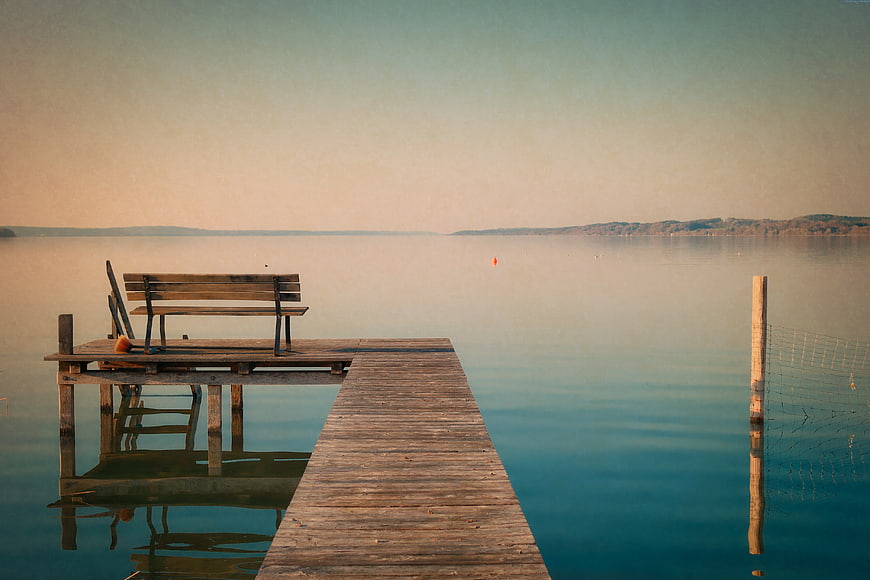 Serene Wooden Dock with Bench on Calm Lake at Sunset