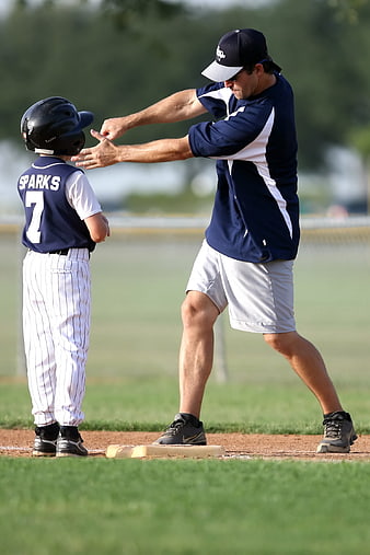 Youth Baseball Coach Teaching Young Player On Field