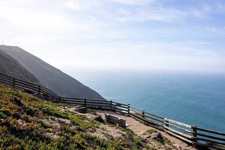 Scenic coastal hiking trail with wooden fence and ocean view