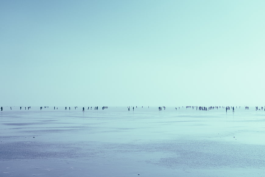 Minimalist winter landscape with people walking on frozen lake