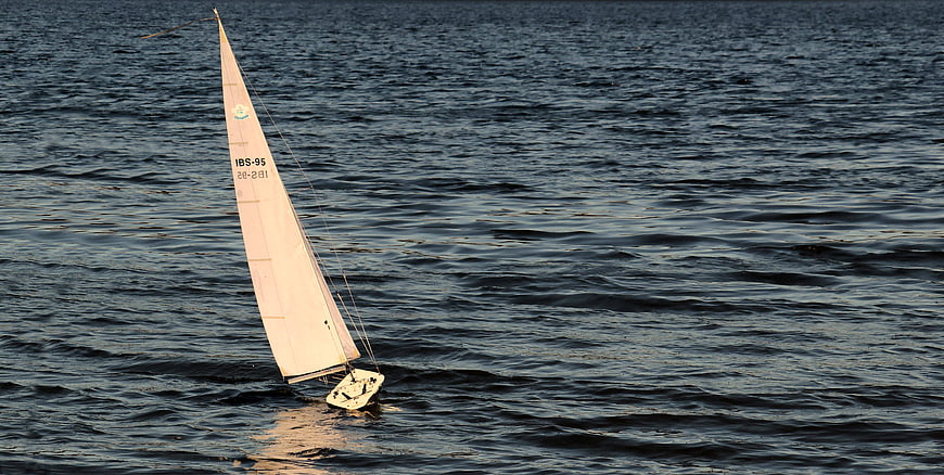 Small RC Sailboat Sailing on Dark Water