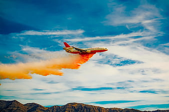 Airplane Dropping Orange Fire Retardant Over Mountains