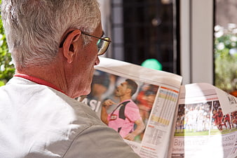 Senior man reading sports newspaper with soccer news
