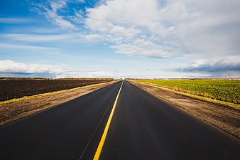 Straight Country Road Through Agricultural Fields Under Blue Sky