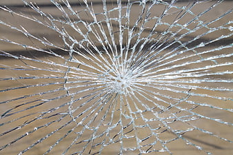 Close-up of shattered glass with radial cracks and impact point