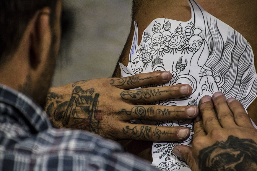 Tattoo artist applying intricate design stencil to client's skin