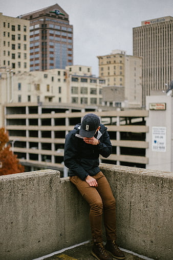 Man sitting on concrete wall in urban city setting