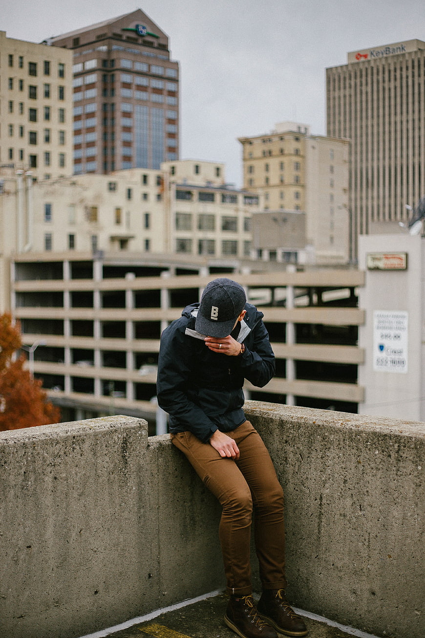 Man sitting on concrete wall in urban city setting