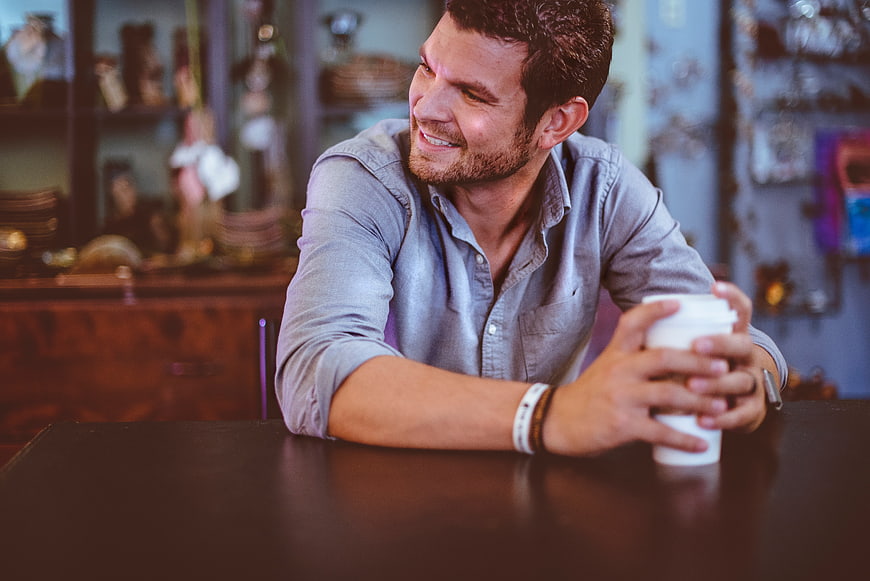 Happy man holding coffee cup in cafe