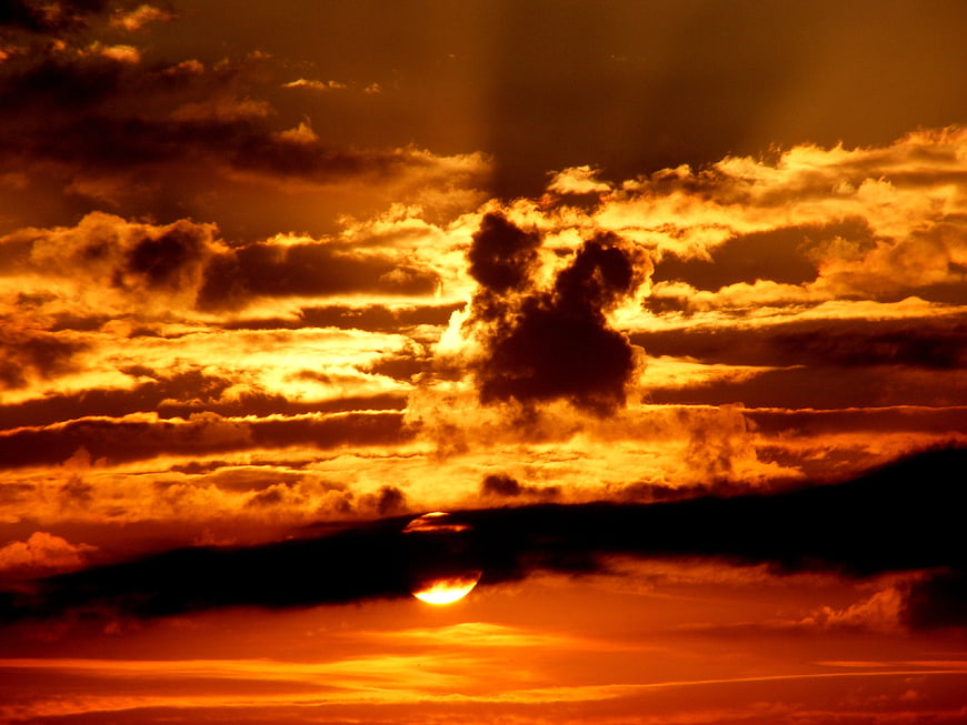 Dramatic orange sunset with dark clouds and sun rays