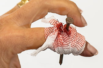 Close-up of finger with nail piercing through bandage