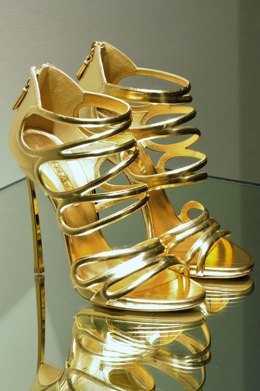 Gold strappy high heels on reflective surface