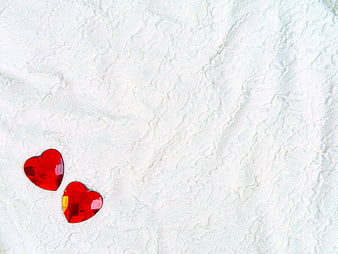 Two Red Heart Gems on White Textured Fabric Background